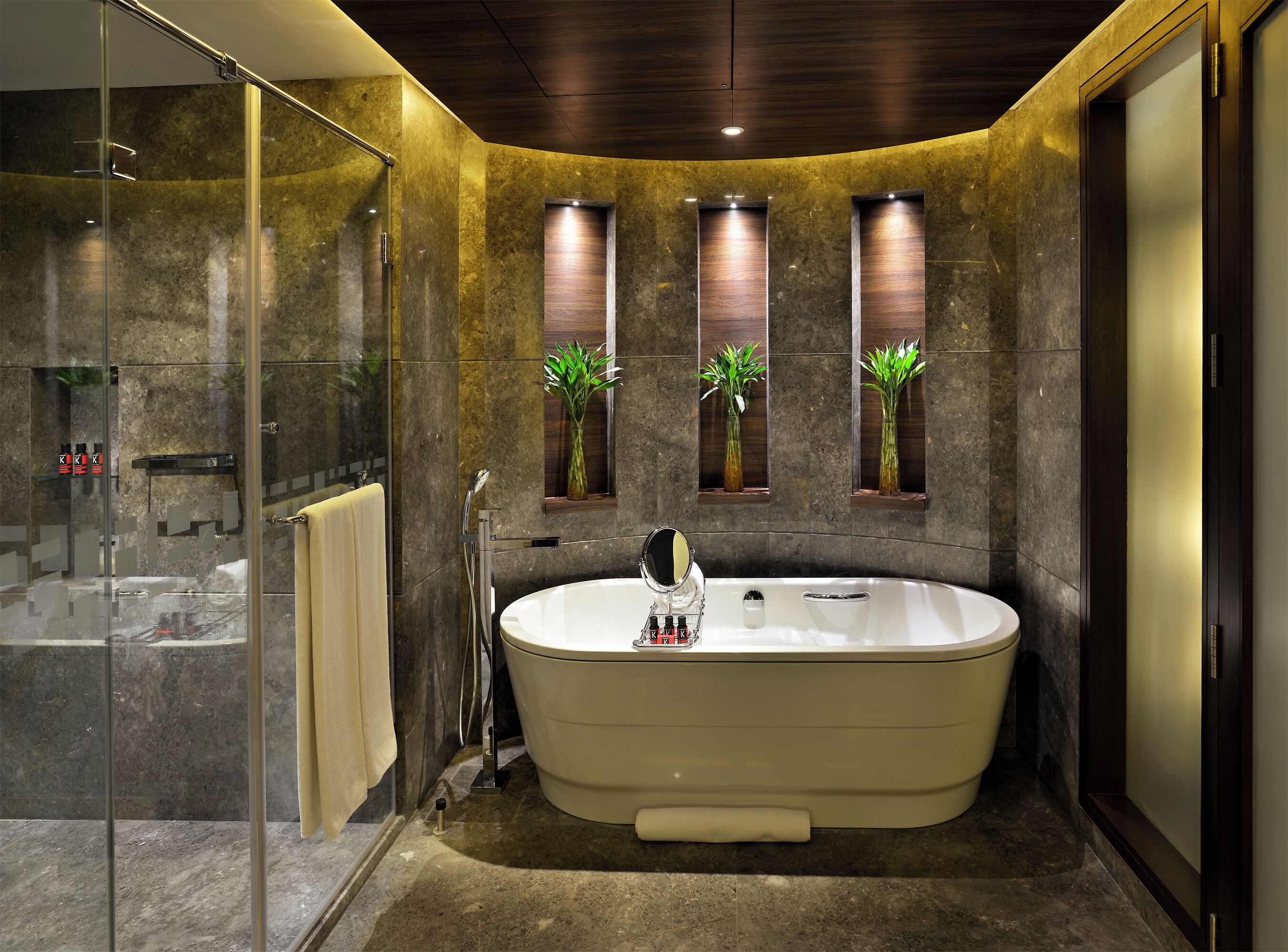 A modern bathroom with a freestanding bathtub, a glass shower enclosure, and two wall-mounted planters with green plants.