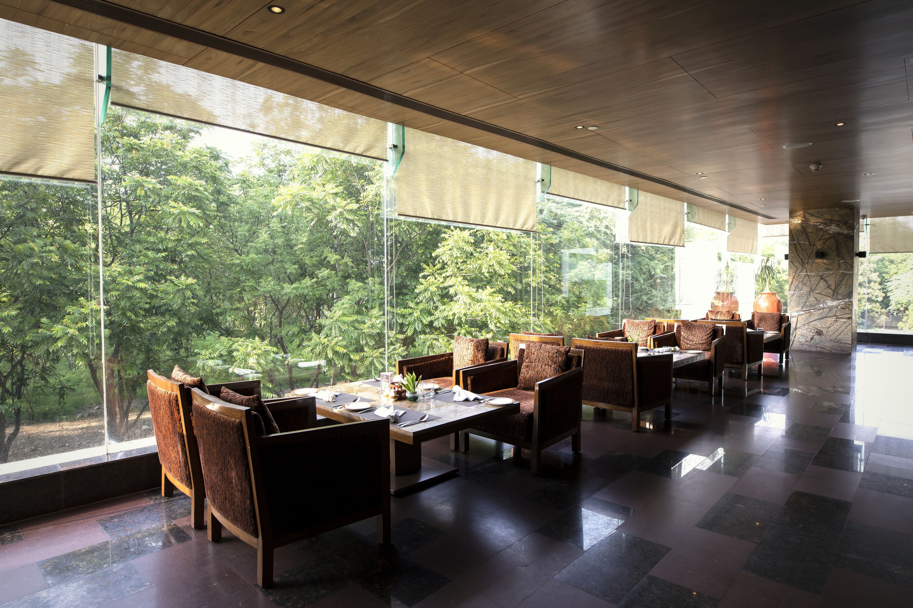 A spacious indoor dining area with large windows offering a view of lush greenery.