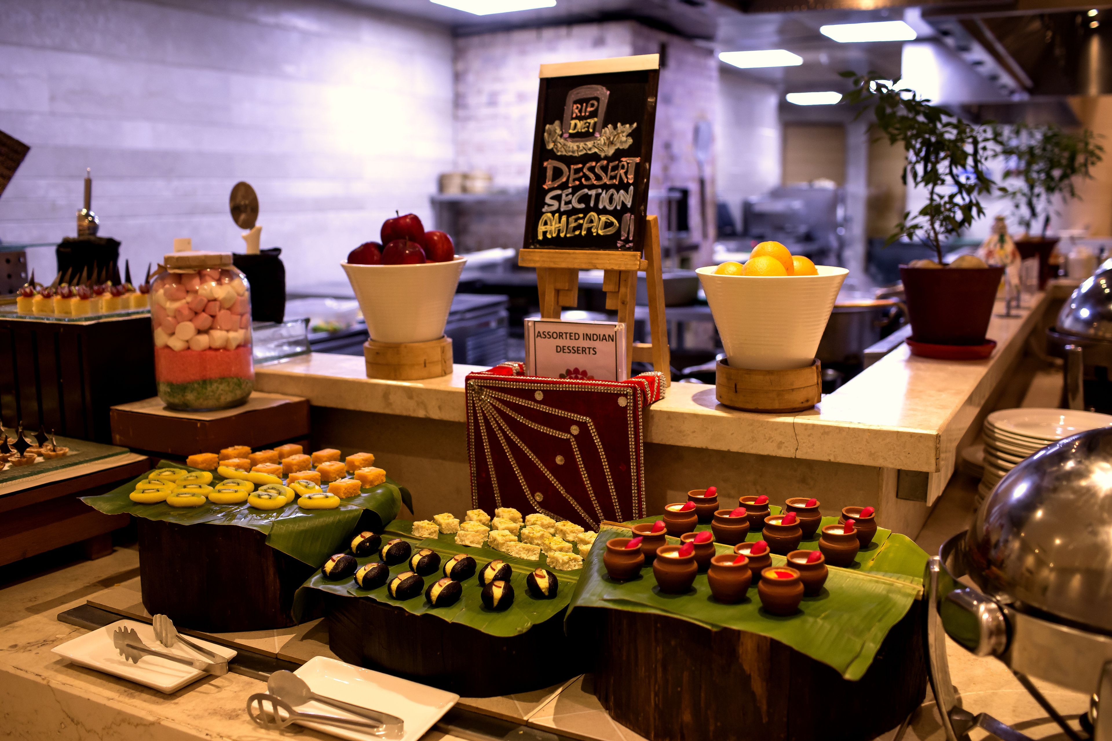 A buffet with various desserts and a sign indicating a dessert section ahead.