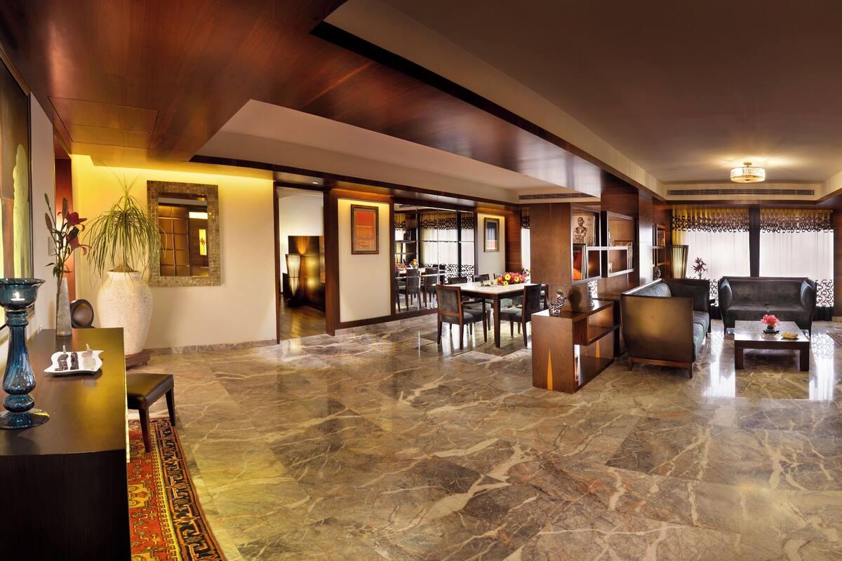 A spacious living area with a dining table, sofa, and a TV mounted on the wall.