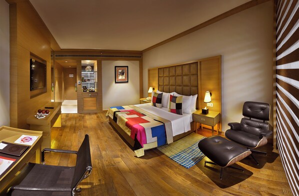 Una habitación de hotel con una cama, un escritorio, una silla, una mesita de noche y una lámpara.
