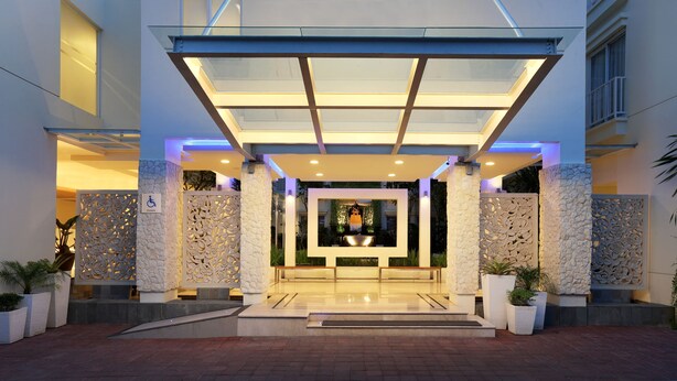A hotel entrance with a glass canopy, stone pillars, and a central decorative area. - ZIA Hotel Kuta (Kuta)