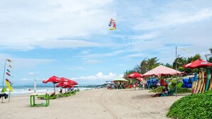 A beach with red umbrellas, green chairs, and a clear sky. - ZIA Hotel Kuta (Kuta)