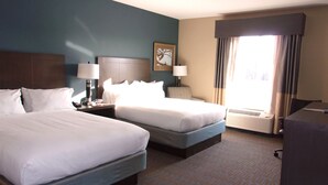 A hotel room with two beds, a desk, a chair, a lamp, and a large window with curtains. - Holiday Inn Express Hotel & Suites Goldsboro - Base Area by IHG (Goldsboro)
