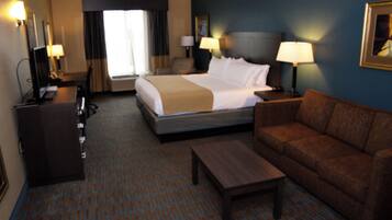 A hotel room with a bed, a sofa, a desk, and a television.