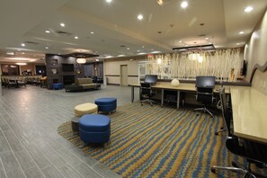A hotel lobby with multiple seating areas, a reception desk, and a large screen TV.