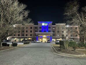 A Holiday Inn Express & Suites building with a central entrance, multiple parking spaces, and surrounding trees. - Holiday Inn Express Hotel & Suites Goldsboro - Base Area by IHG (Goldsboro)