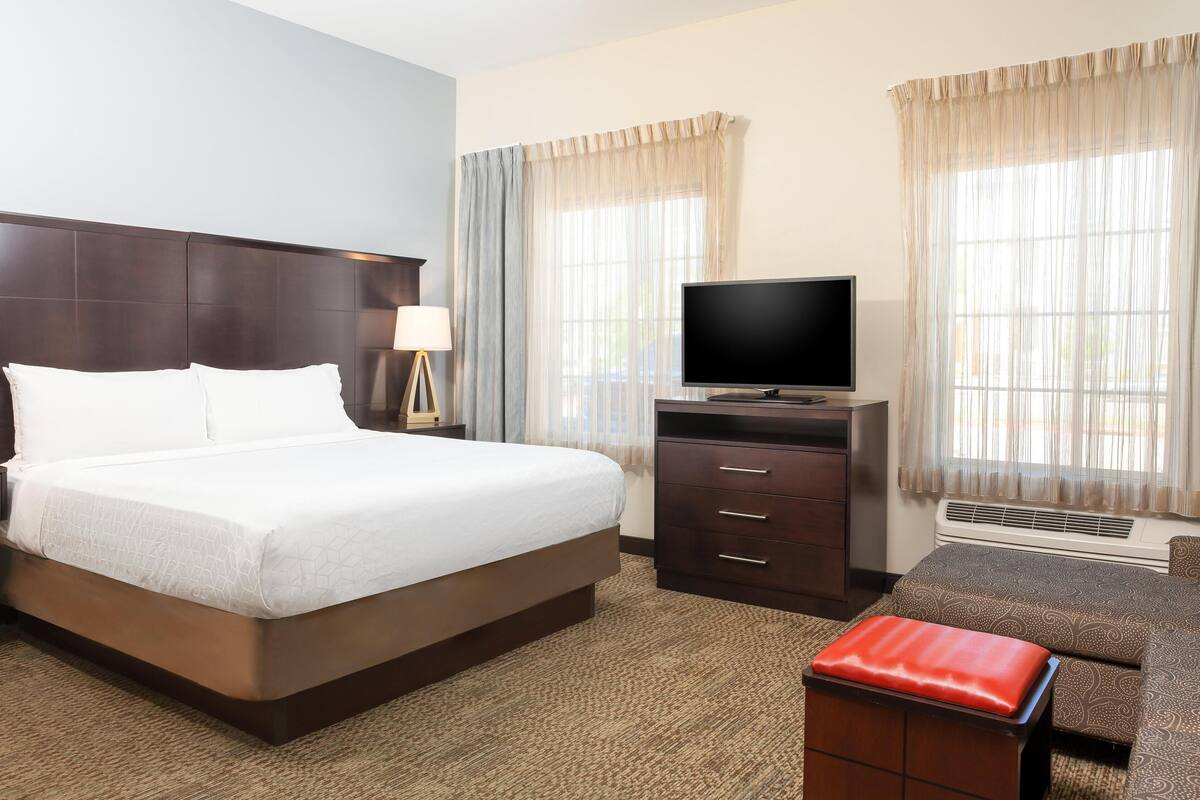 Una habitación de hotel con una cama grande, televisión, escritorio y una silla.