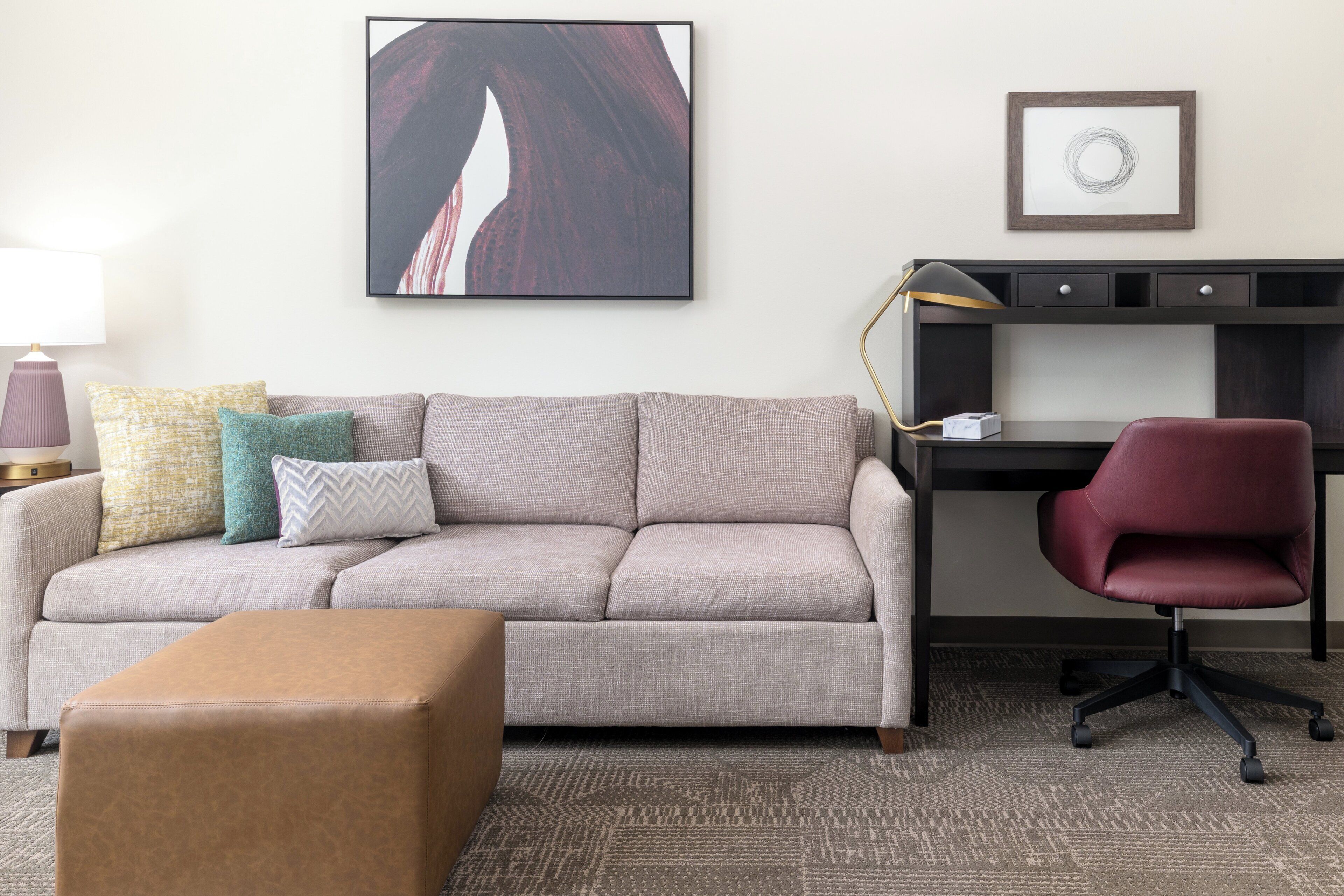 Un salon comprenant un canapé, un pouf et un bureau avec une chaise.