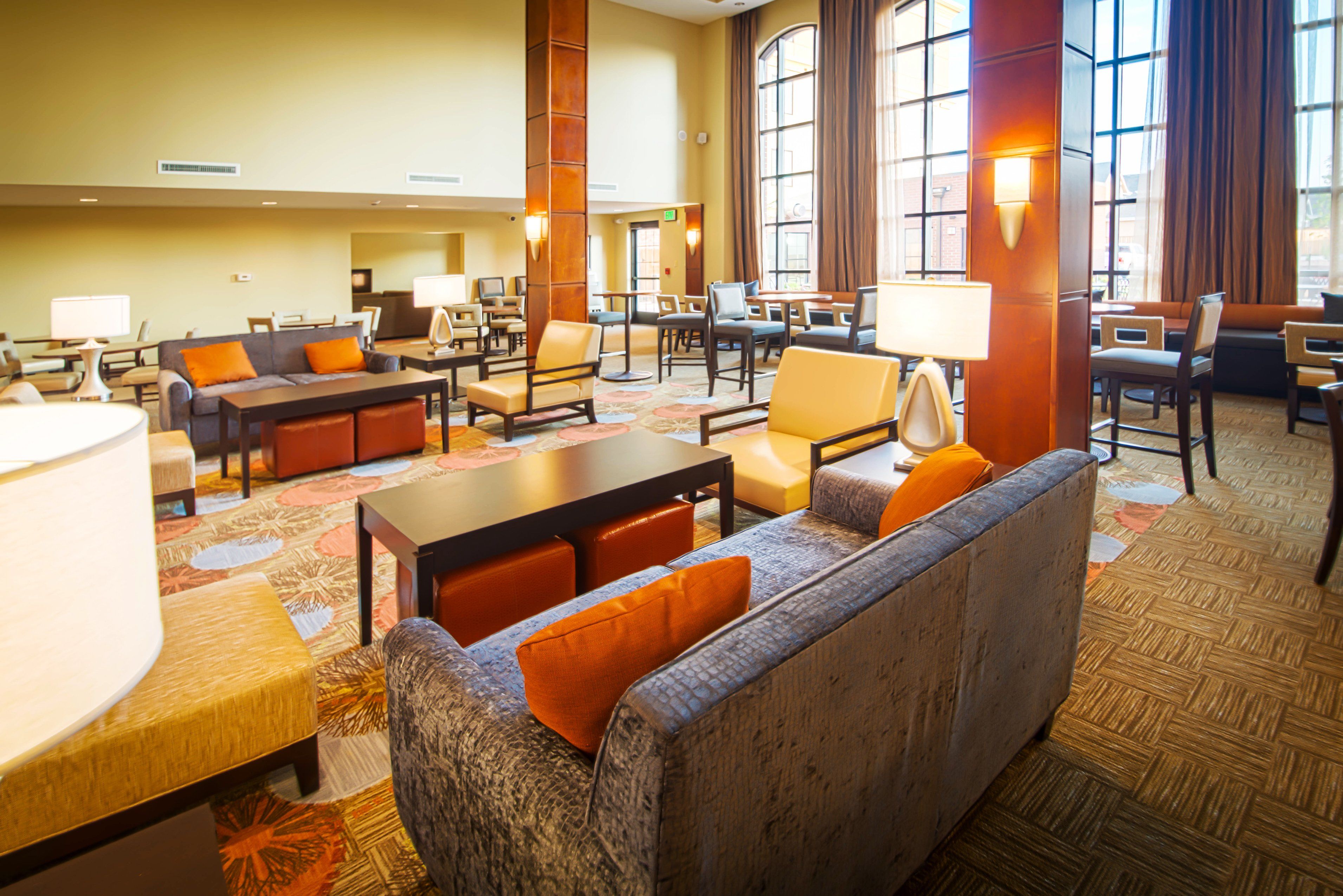 A hotel lobby with a seating area, tables, and a large window.
