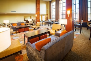 A hotel lobby with a seating area, tables, and a large window. - Staybridge Suites Denver-Central Park by IHG (Denver)