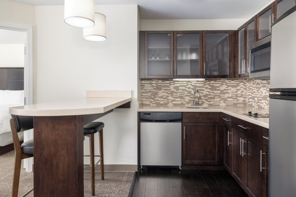 A modern kitchen with dark wooden cabinets, a white countertop, and a dishwasher.