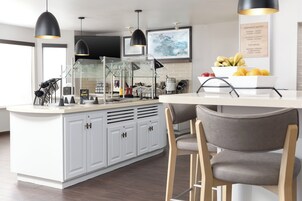 Una cocina moderna con armarios blancos, una isla central e iluminación colgante.