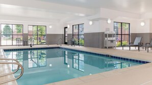 An indoor swimming pool with clear glass walls, a tiled floor, and a towel rack with towels. - Staybridge Suites Denver-Central Park by IHG (Denver)