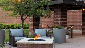 An outdoor seating area with a fire pit, wicker furniture, and potted plants. - Staybridge Suites Denver-Central Park by IHG (Denver)