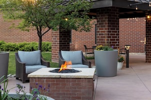 Un espacio al aire libre con una chimenea, muebles de mimbre y plantas en macetas.