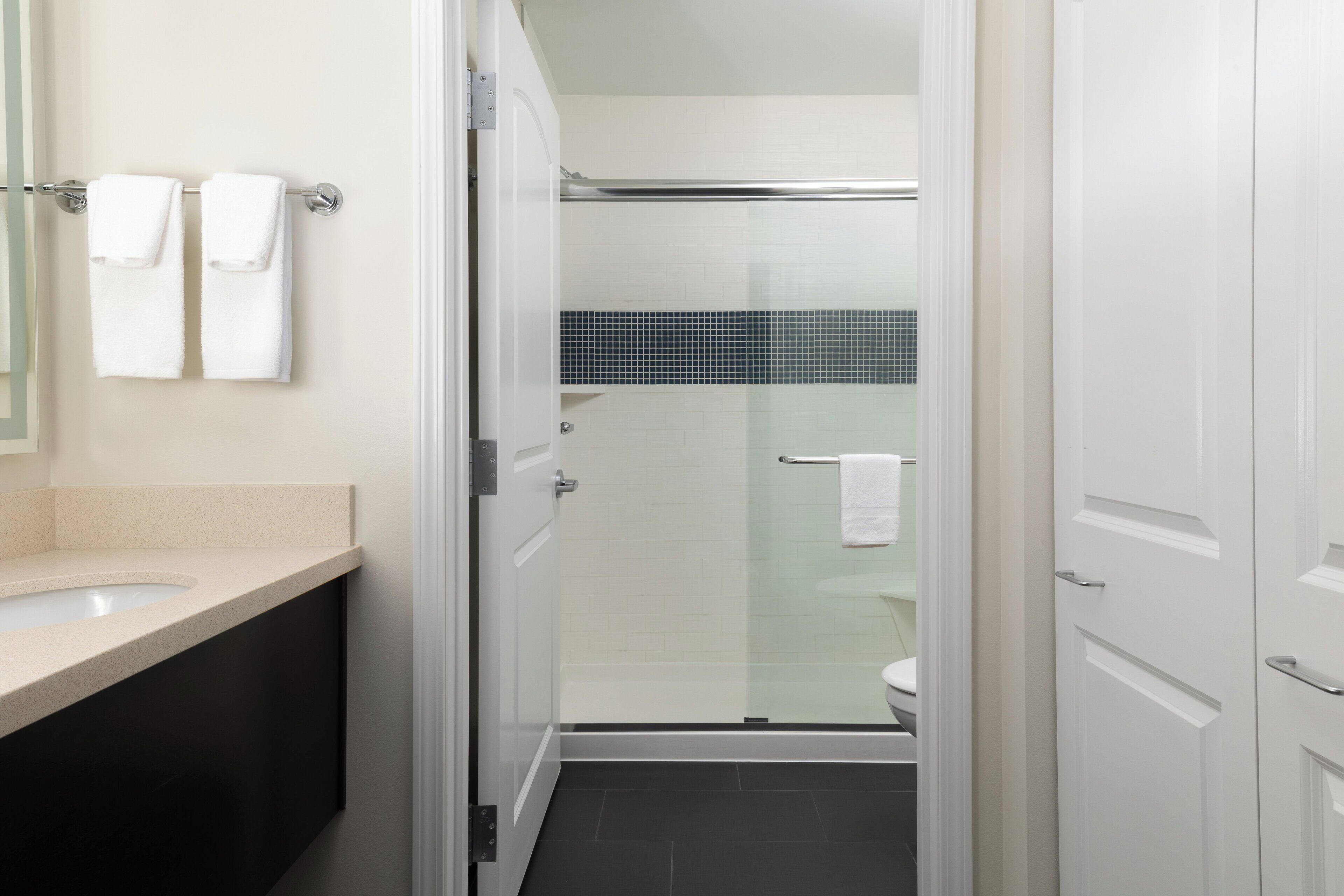 A modern bathroom with a glass-enclosed shower, a white sink, and a black countertop.