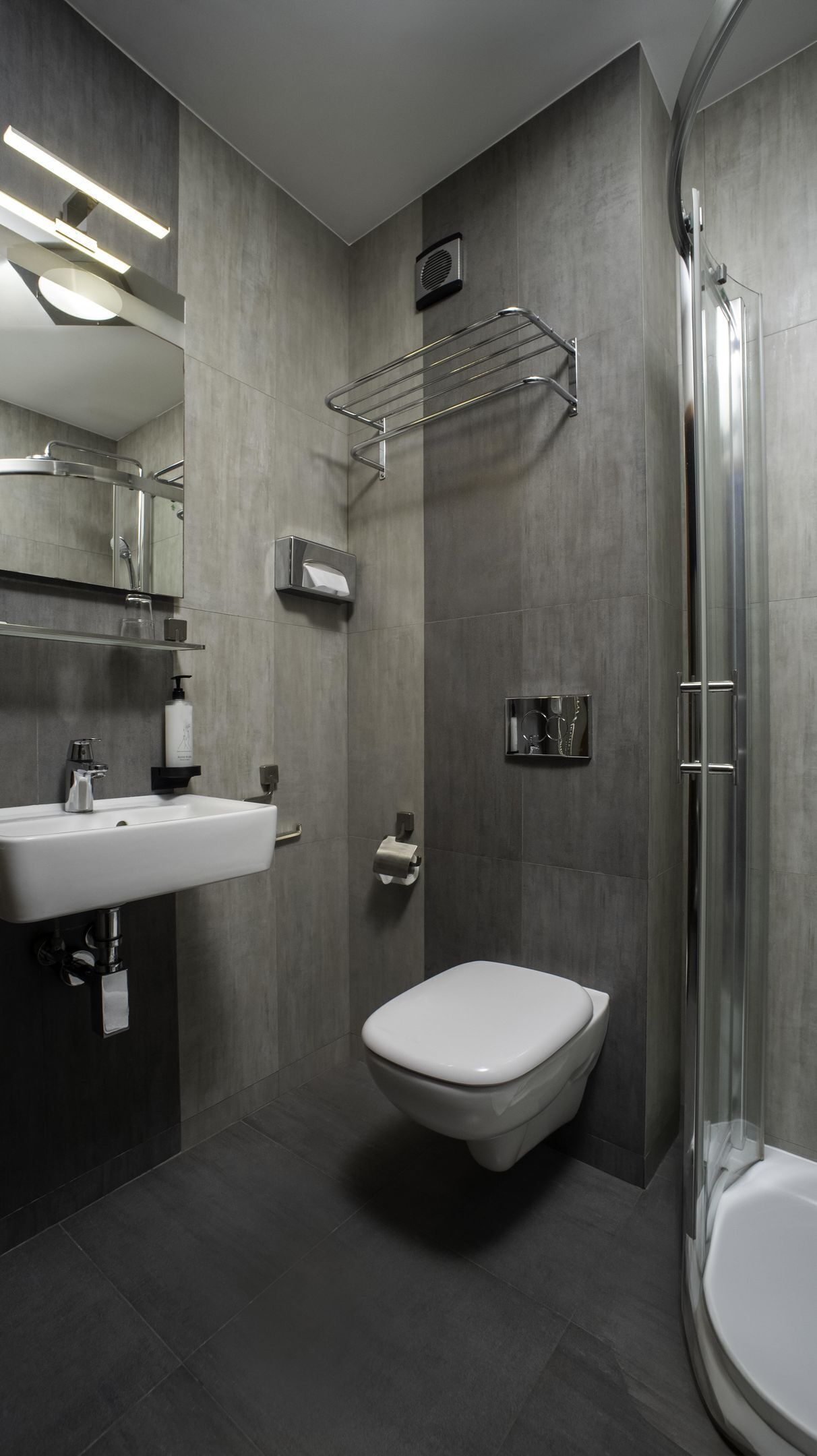 A modern bathroom with a white sink, a toilet, and a shower.