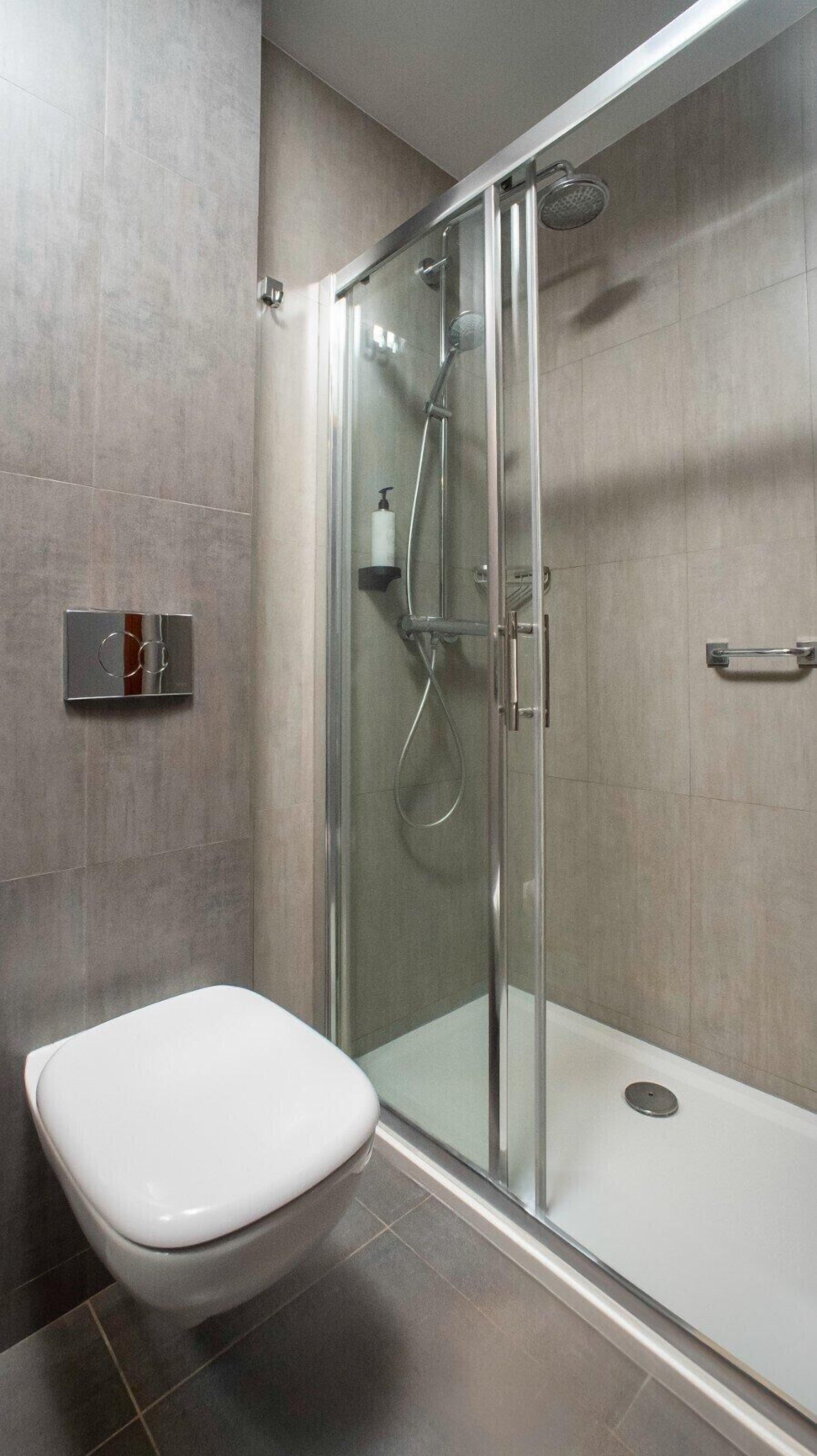 A modern bathroom with a glass-enclosed shower, a white toilet, and a towel rack.