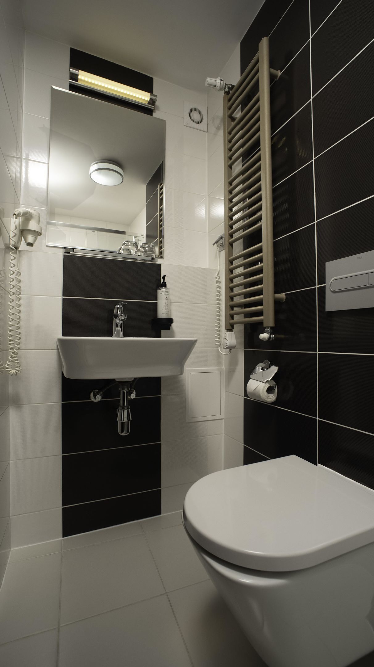 A modern bathroom with a white sink, a toilet, a towel rack, and a mirror.