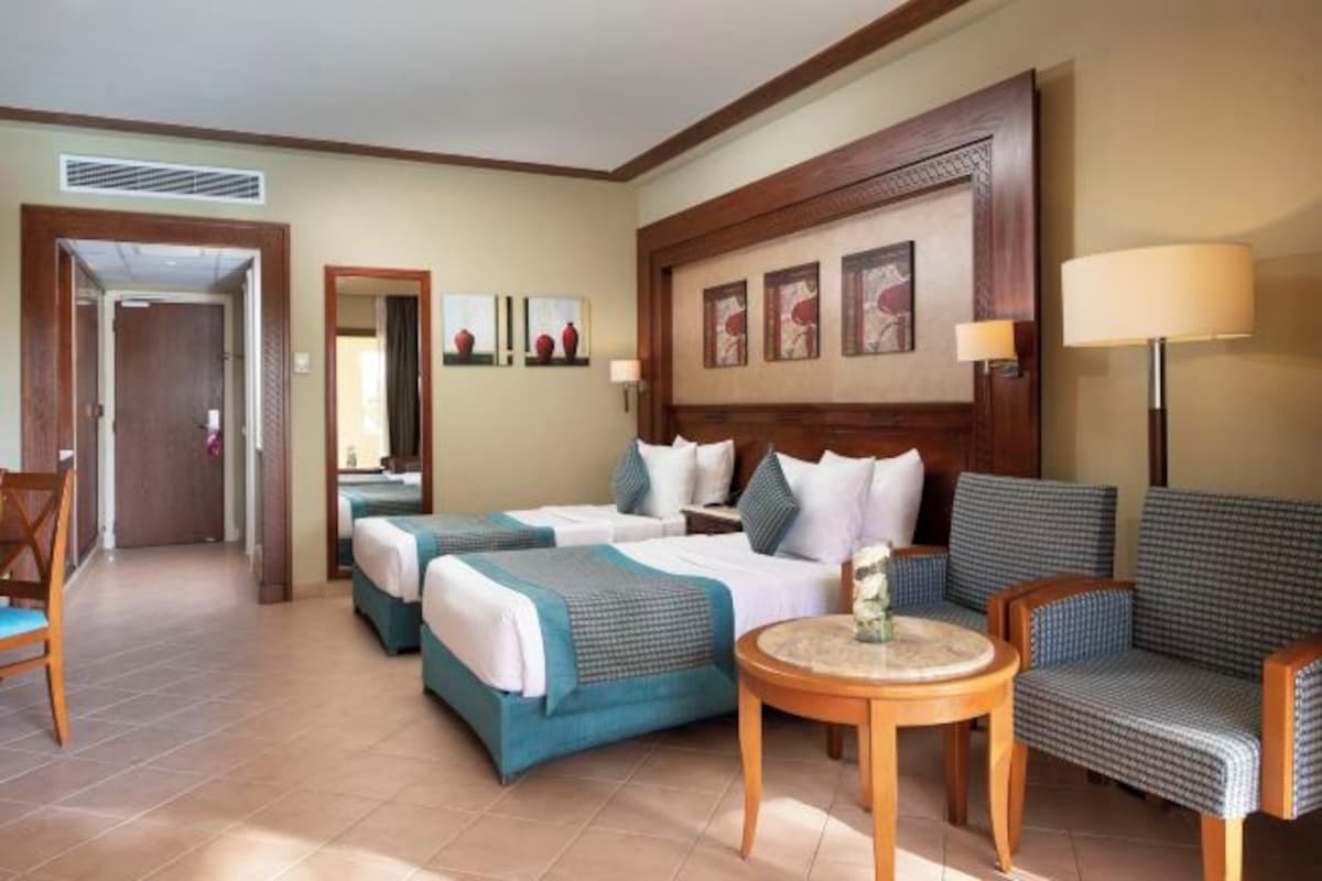 Une chambre d’hôtel avec deux lits, un canapé, une petite table et une chaise.