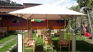 An outdoor seating area with wooden chairs and a large umbrella. - Kurumi (Cusco)