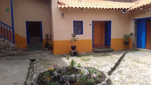 A courtyard with a stone floor, potted plants, and a flower bed. - Kurumi (Cusco)