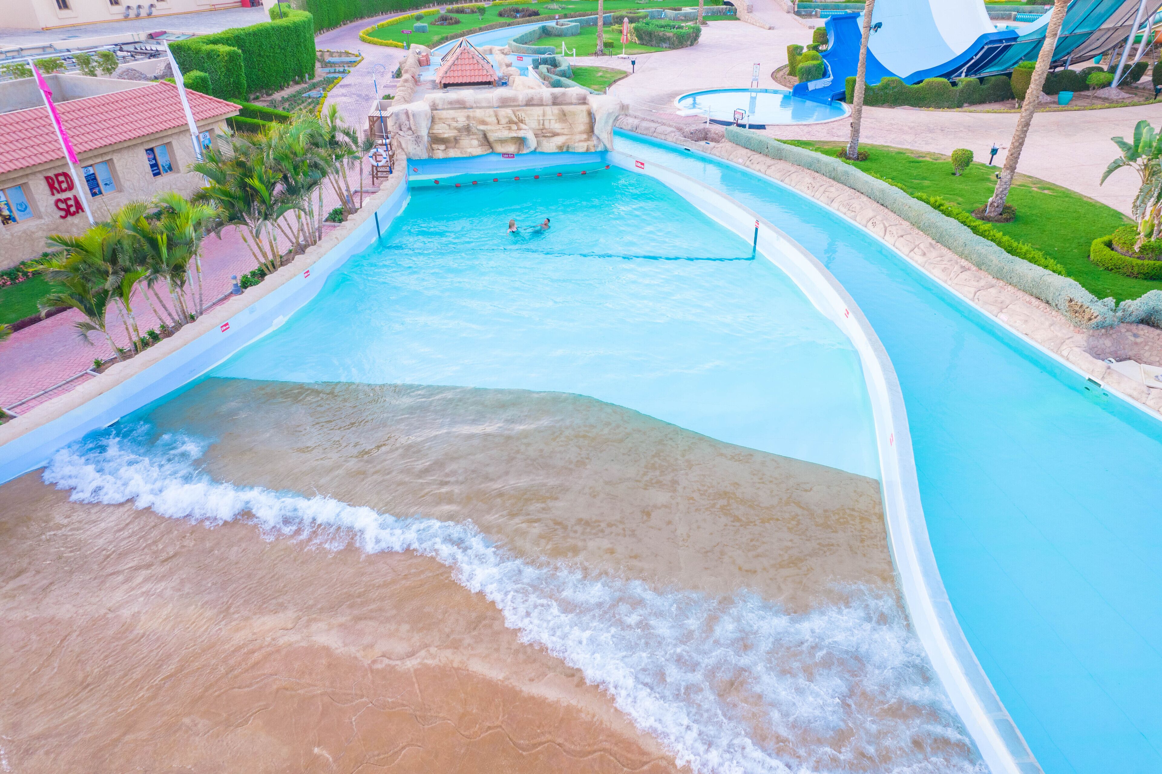 A water park with a wave pool, palm trees, and a building labeled "RED SEA".