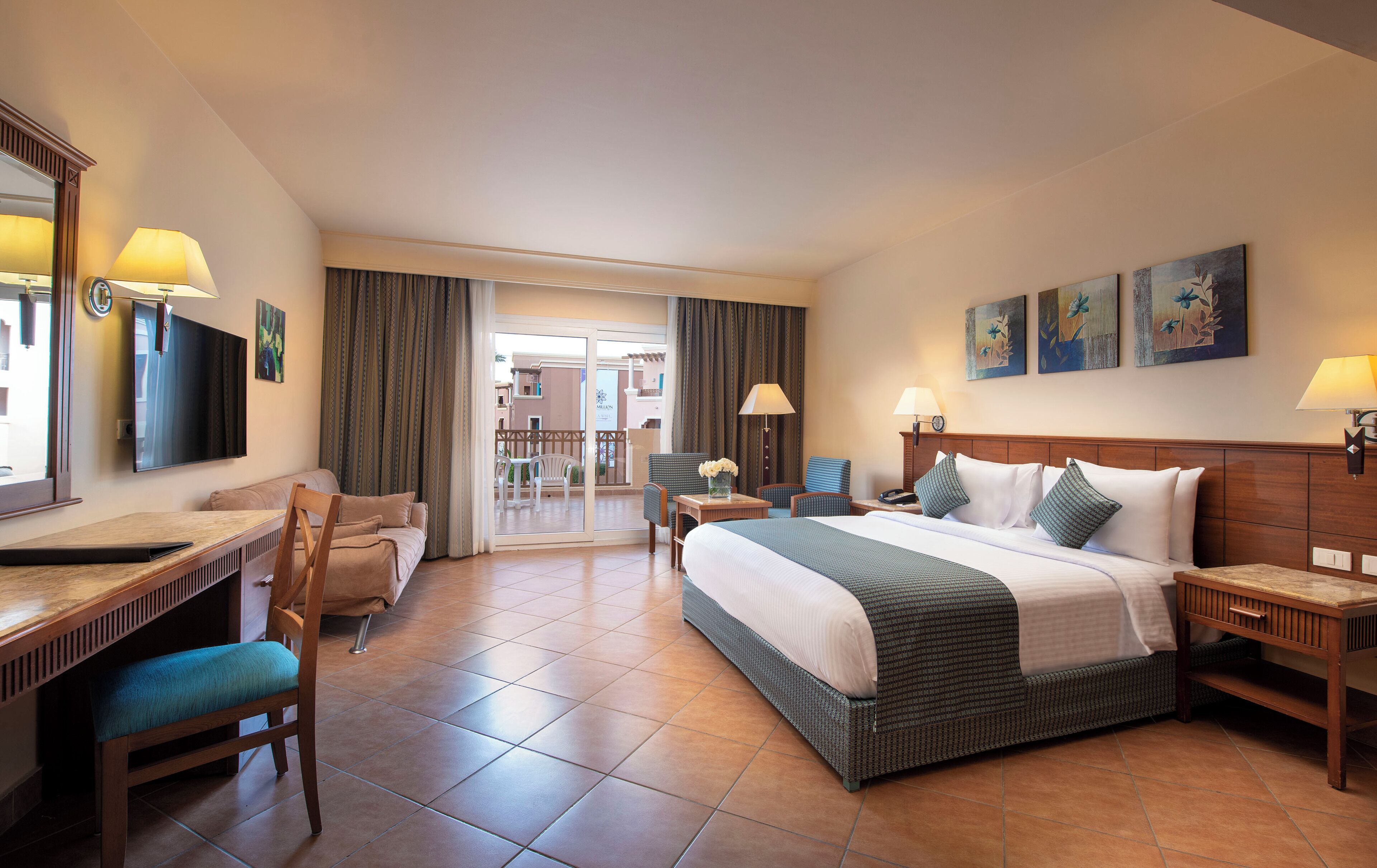 A hotel room with a bed, a desk, a chair, a table, and a balcony.