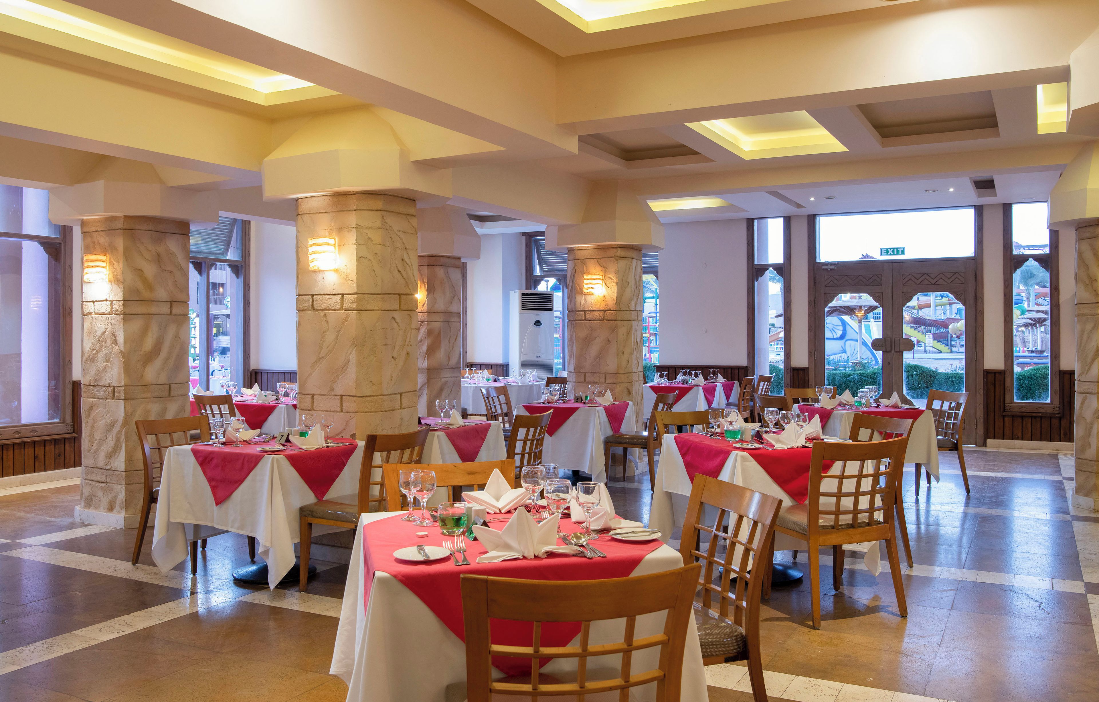 A restaurant with multiple tables, stone pillars, and a view of an outdoor area.