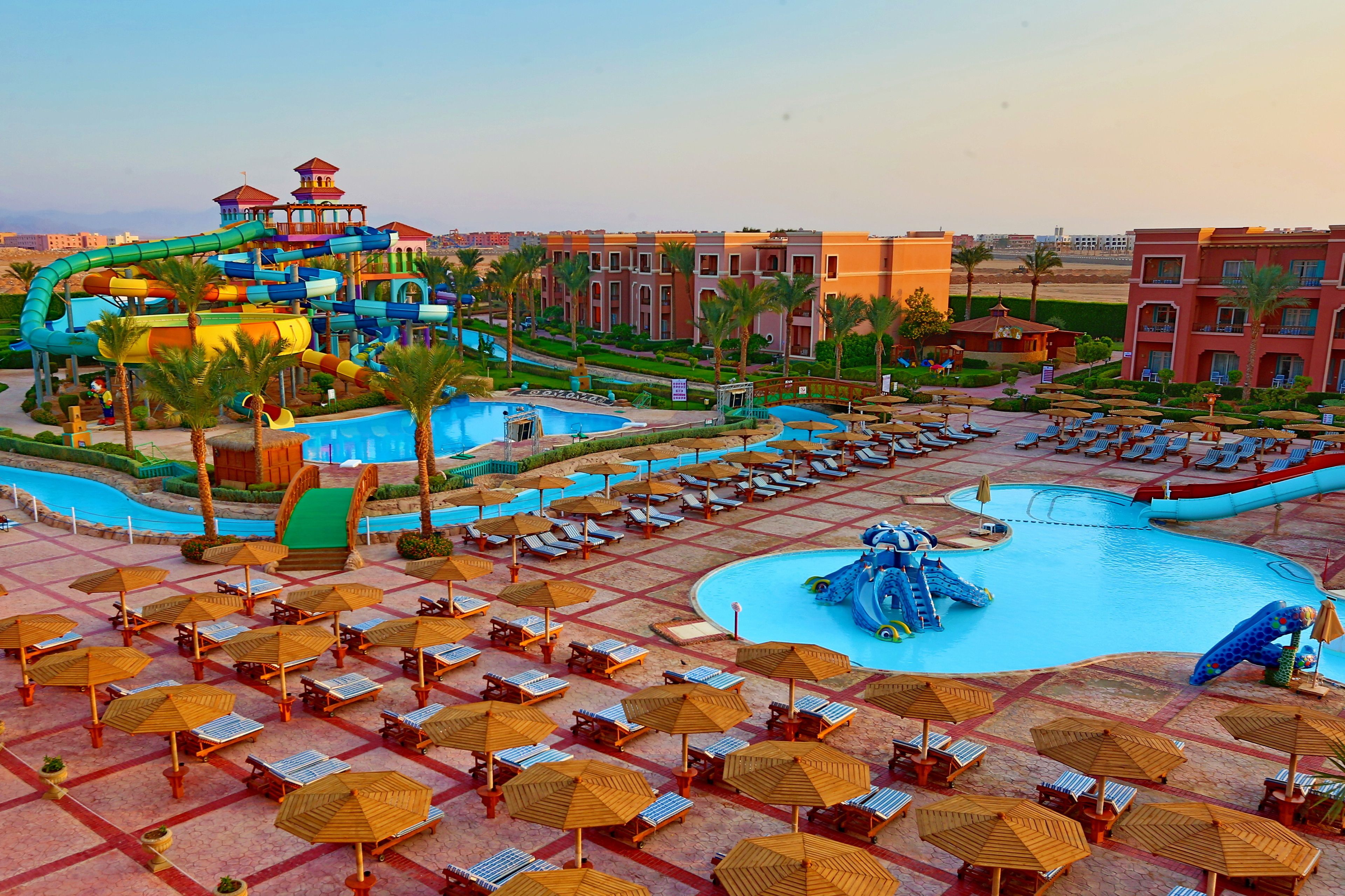 A water park with slides and pools, surrounded by lounge areas with umbrellas and sun loungers.