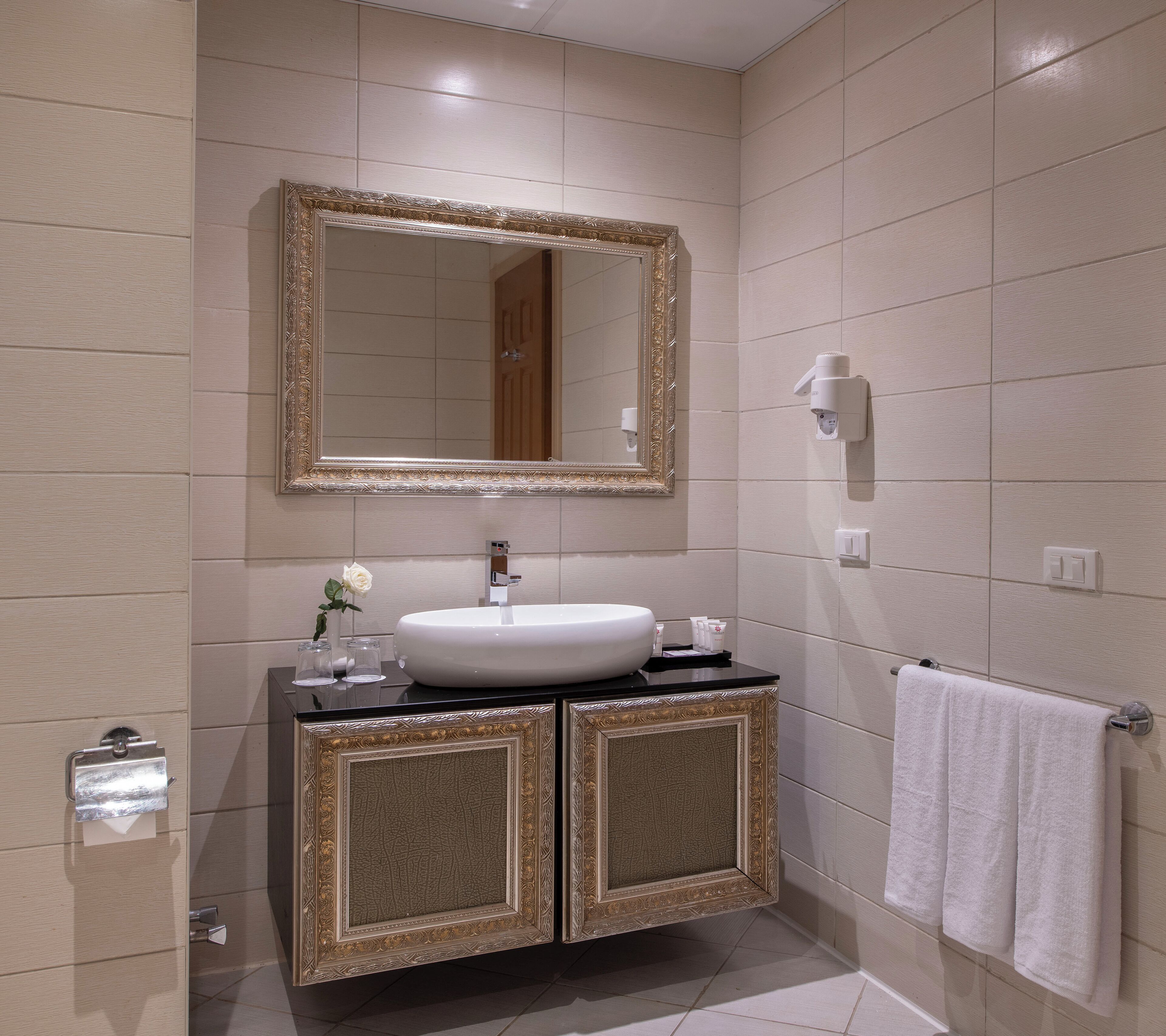 A bathroom with a large mirror, a white sink, and a towel rack.