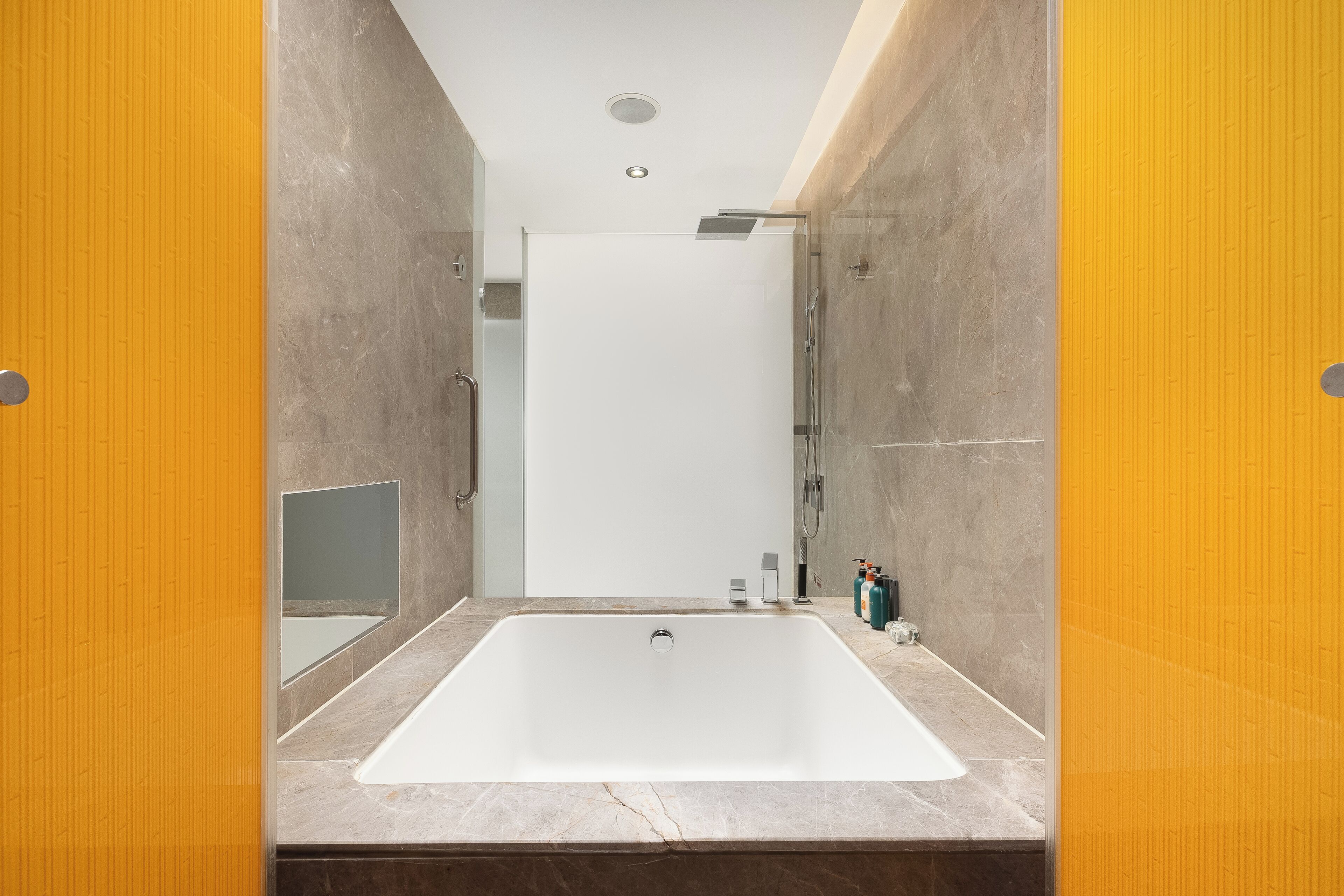 Une salle de bain moderne avec une grande baignoire blanche, une douche en verre et un comptoir en marbre.
