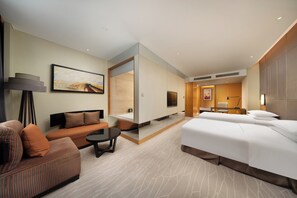 Une chambre d’hôtel moderne équipée d’un canapé, d’un lit, d’un bureau et d’une télévision.