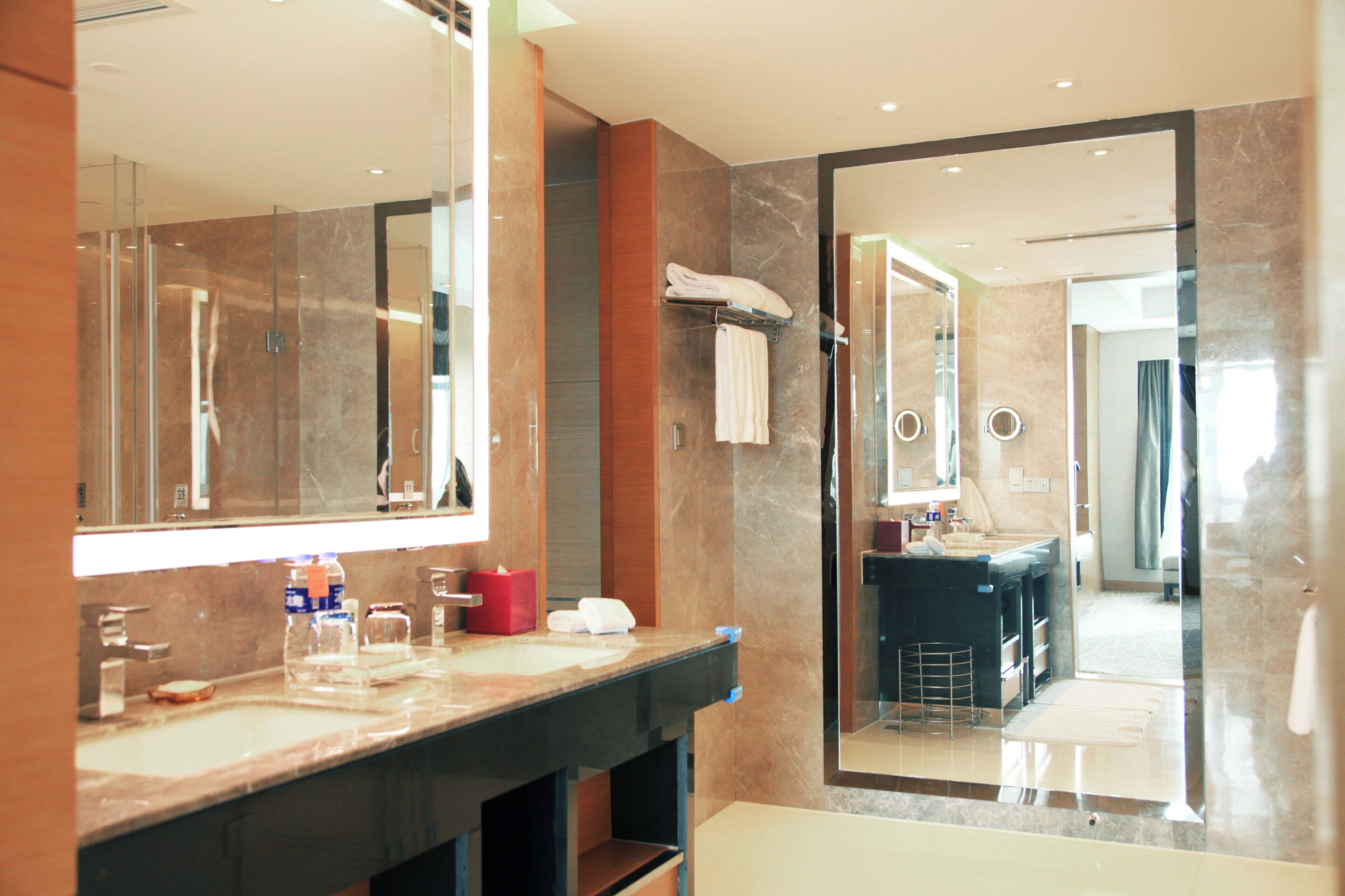 A modern bathroom with a large mirror, a vanity with a sink, and a shower area.
