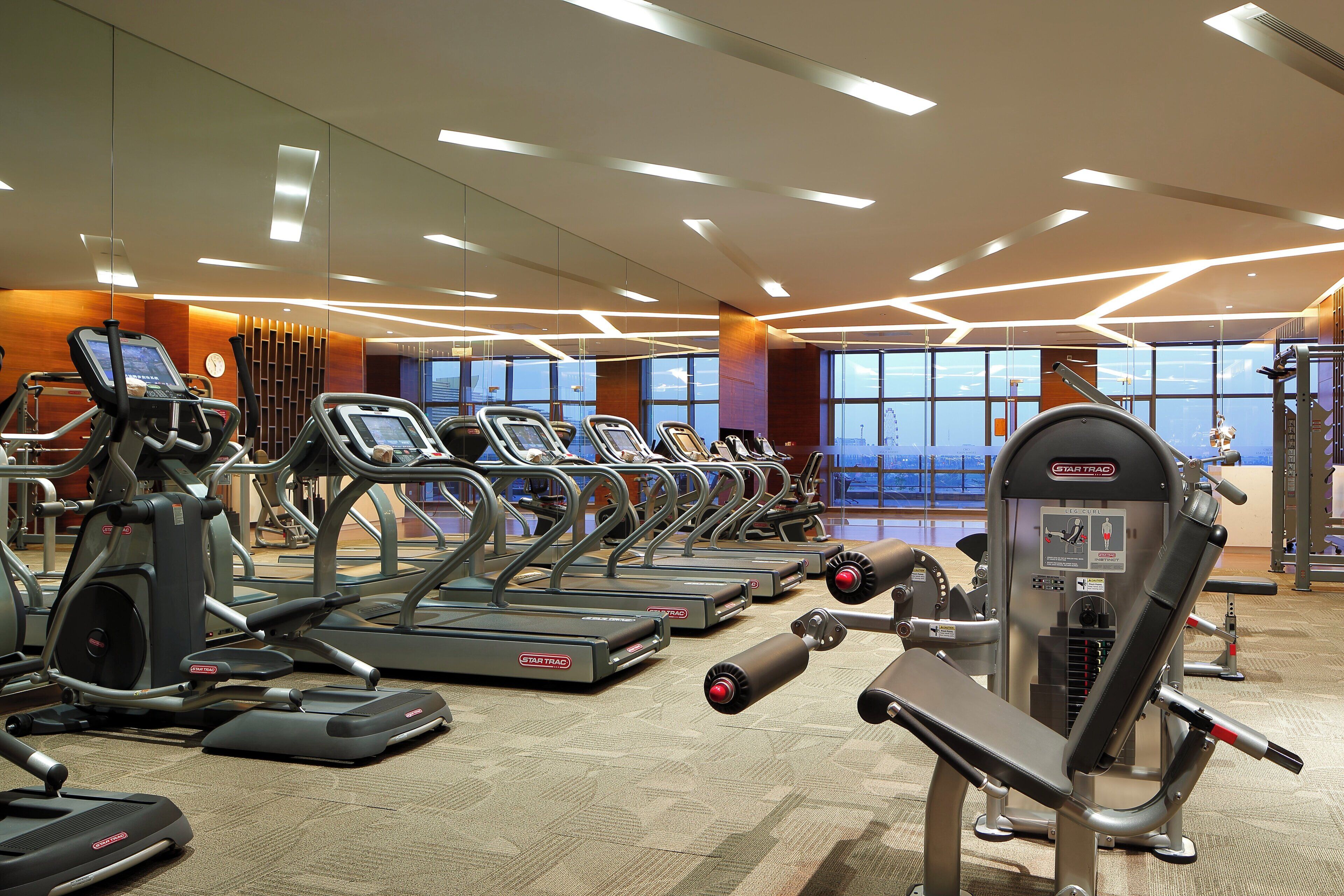 Een fitnessruimte met loopbanden, elliptische trainers en gewichten.