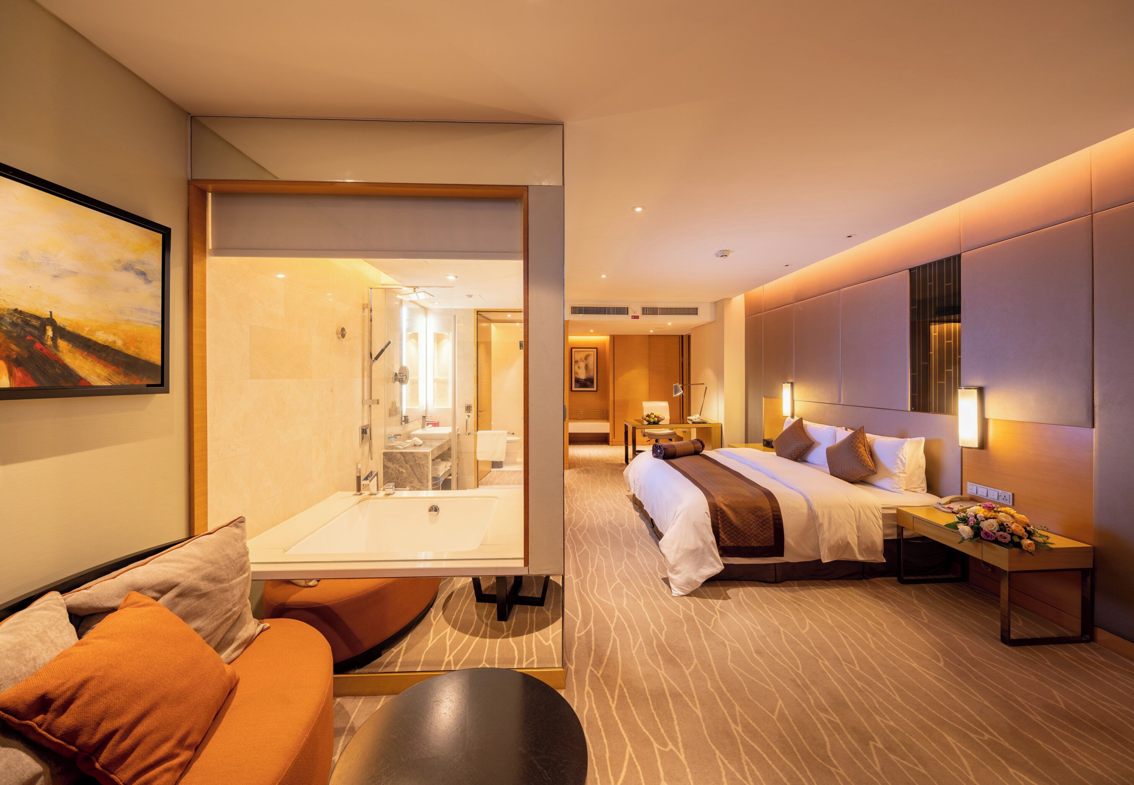 Ein Hotelzimmer mit Bett, Schreibtisch, Stuhl, Sofa und einem durchgegangenen Tür sichtbaren Badezimmer.