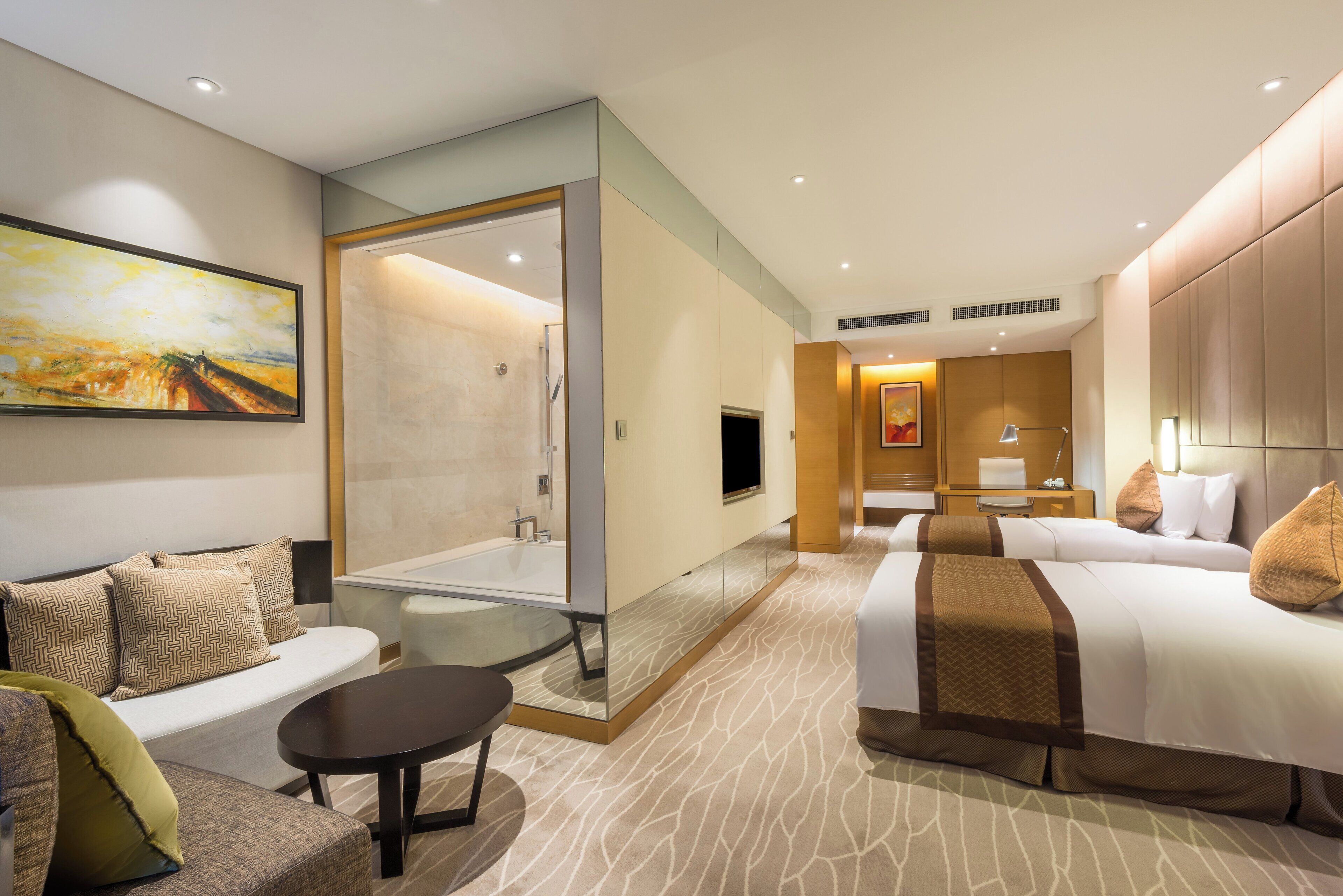 A modern hotel room with a sofa, a bed, a small table, and a shower area.