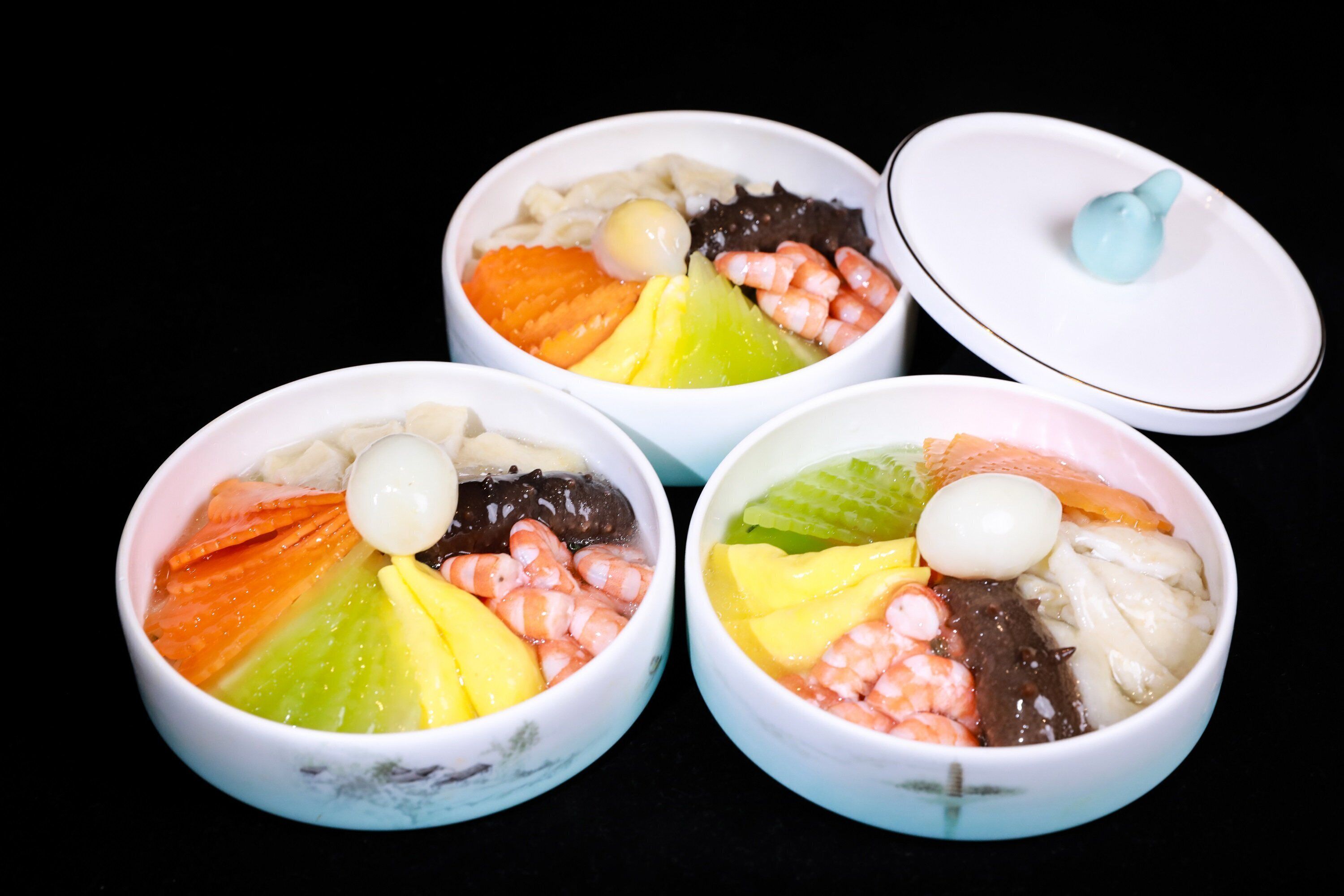 Three bowls of assorted food items, each with a lid.