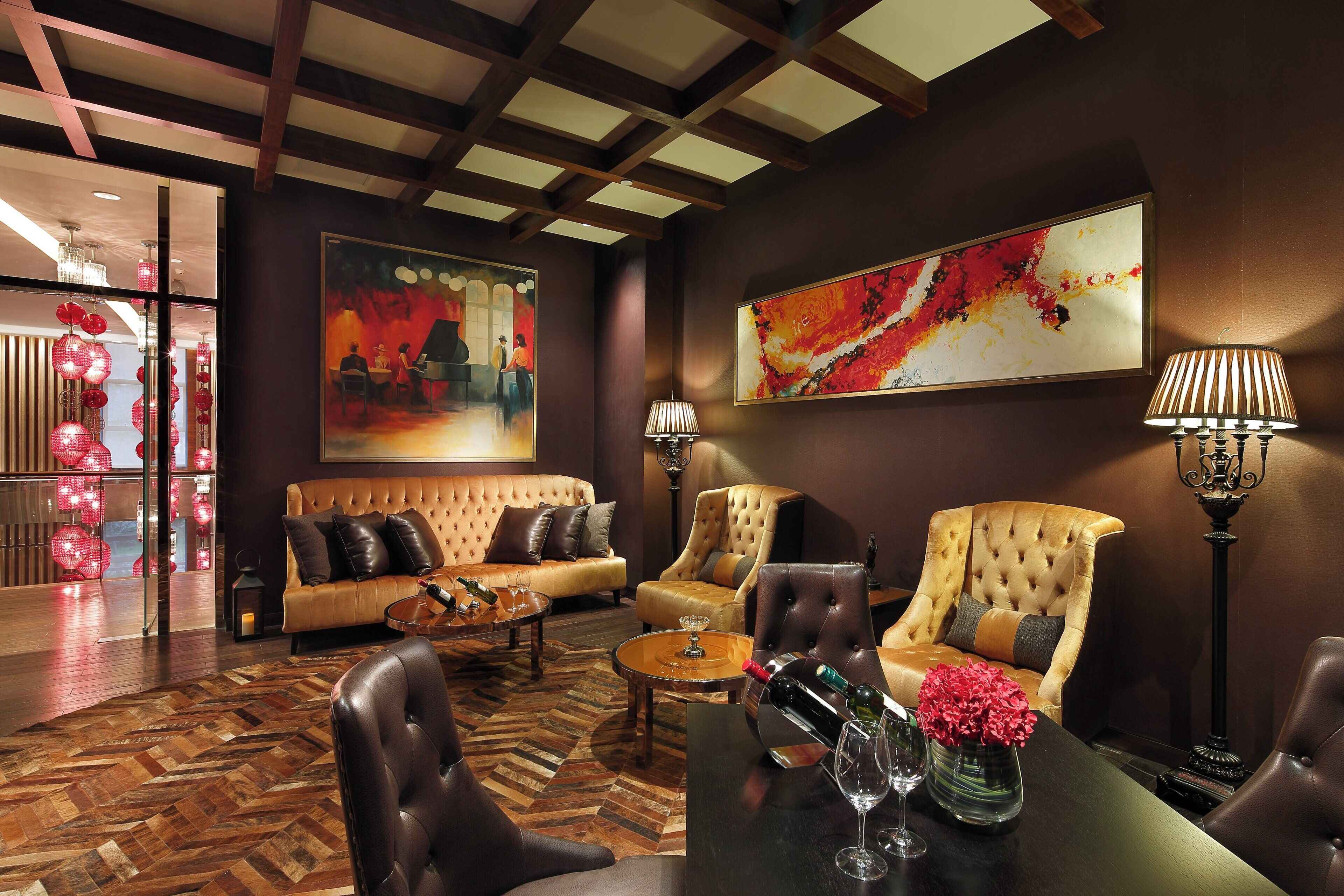 A room with a sofa, armchairs, a coffee table, and a painting on the wall.