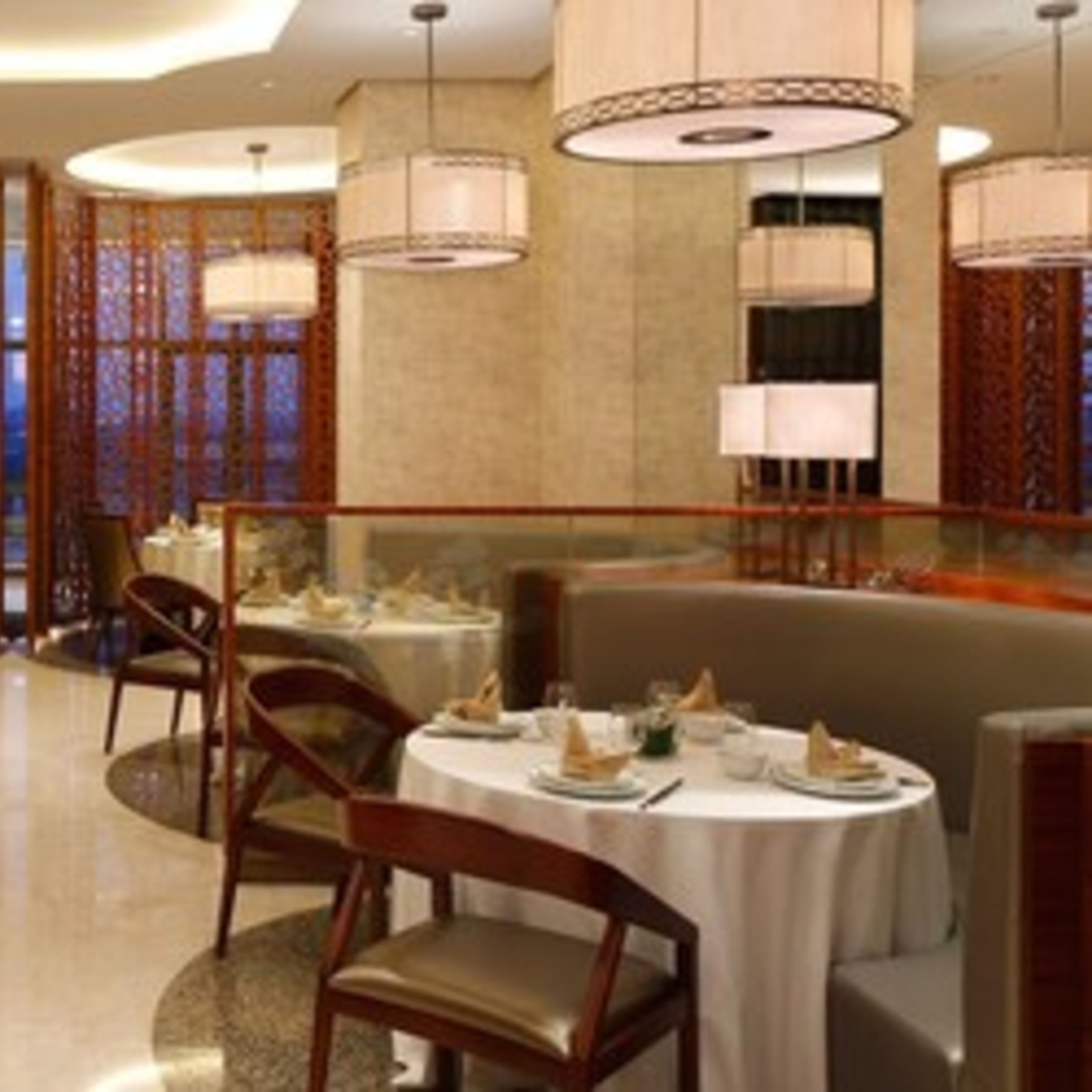 A dining area with round tables, chairs, and hanging lamps.