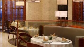 A dining area with round tables, chairs, and hanging lamps.