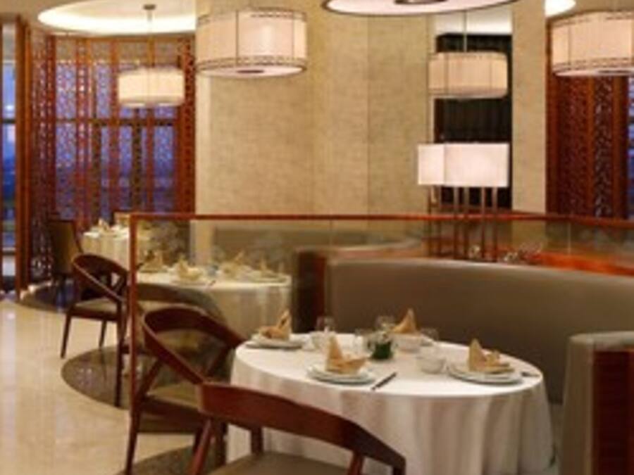 A dining area with round tables, chairs, and hanging lamps.