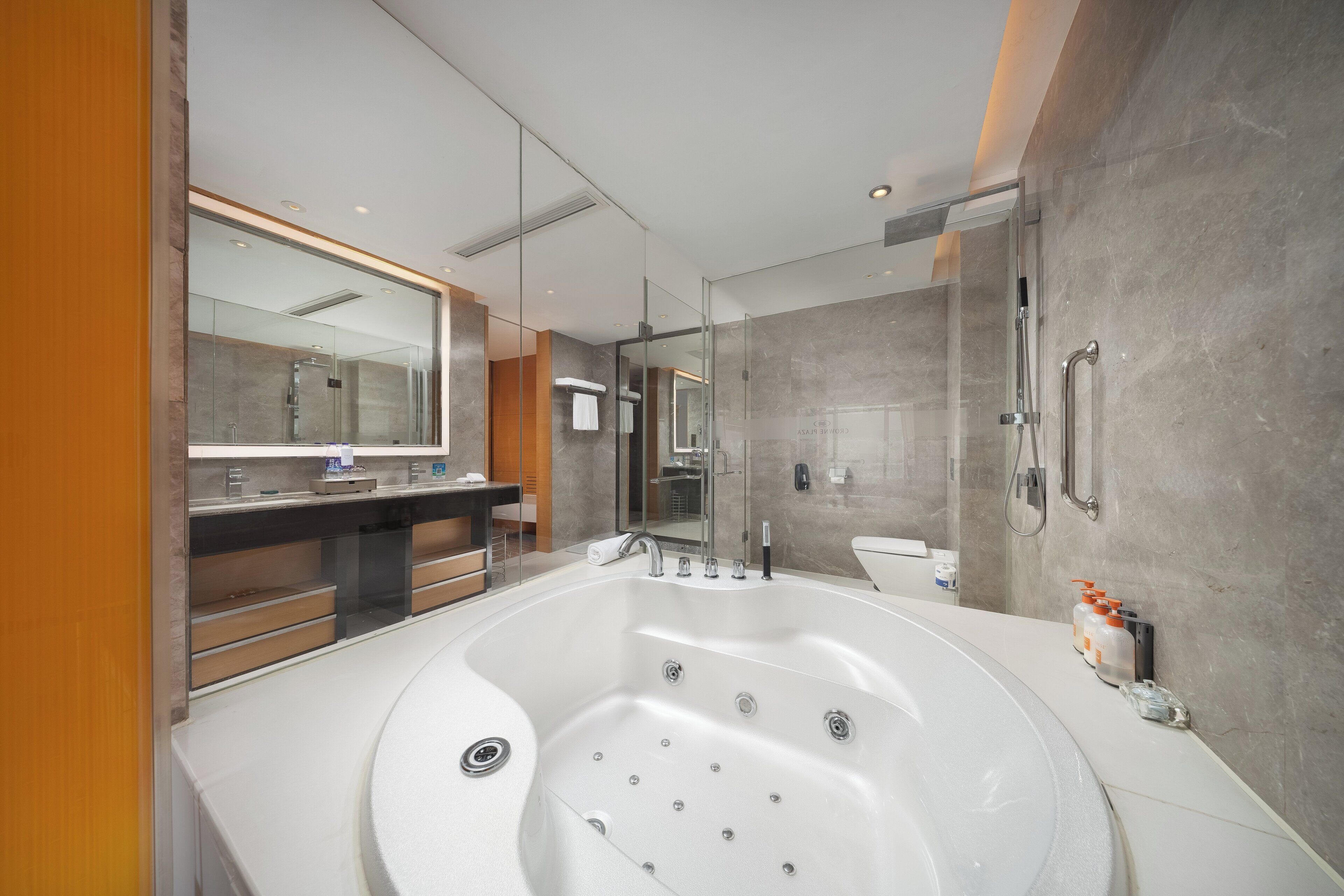 Un baño moderno con una bañera grande, ducha con cerramiento de vidrio y tocador con espejo.