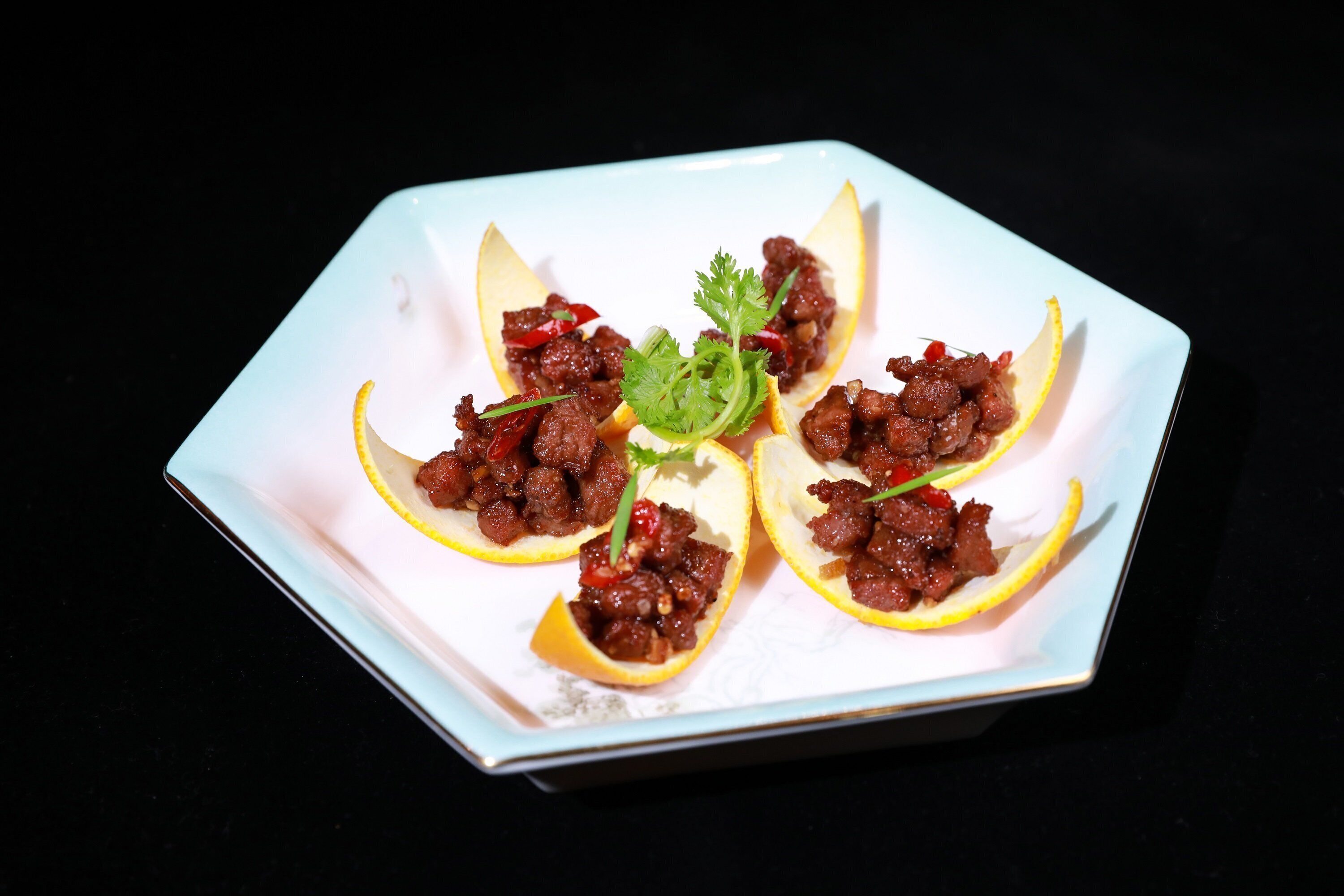 A square plate with a white interior and a light blue exterior, containing food items arranged in a circular pattern.