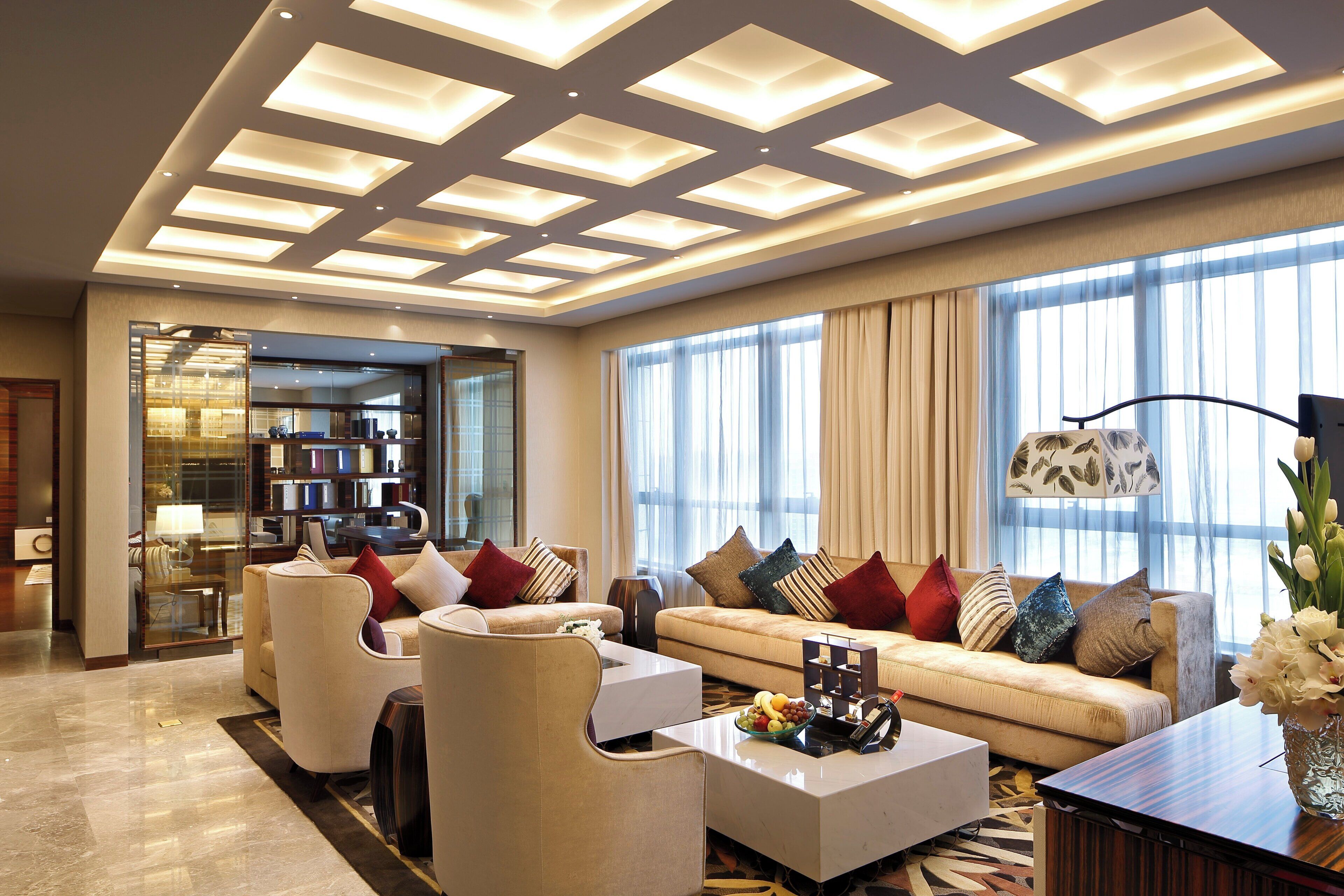 A modern living room with a sofa, armchairs, a coffee table, and a bookshelf.