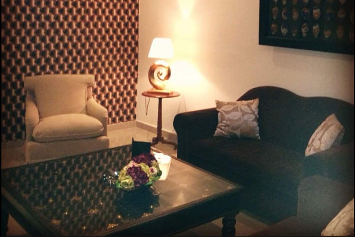 A living room with a patterned wallpaper, a sofa, a chair, a coffee table, and a lamp.