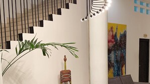 Een moderne woonkamer met een donkerbruine bank, een witte salontafel en een trap met zwarte leuningen.