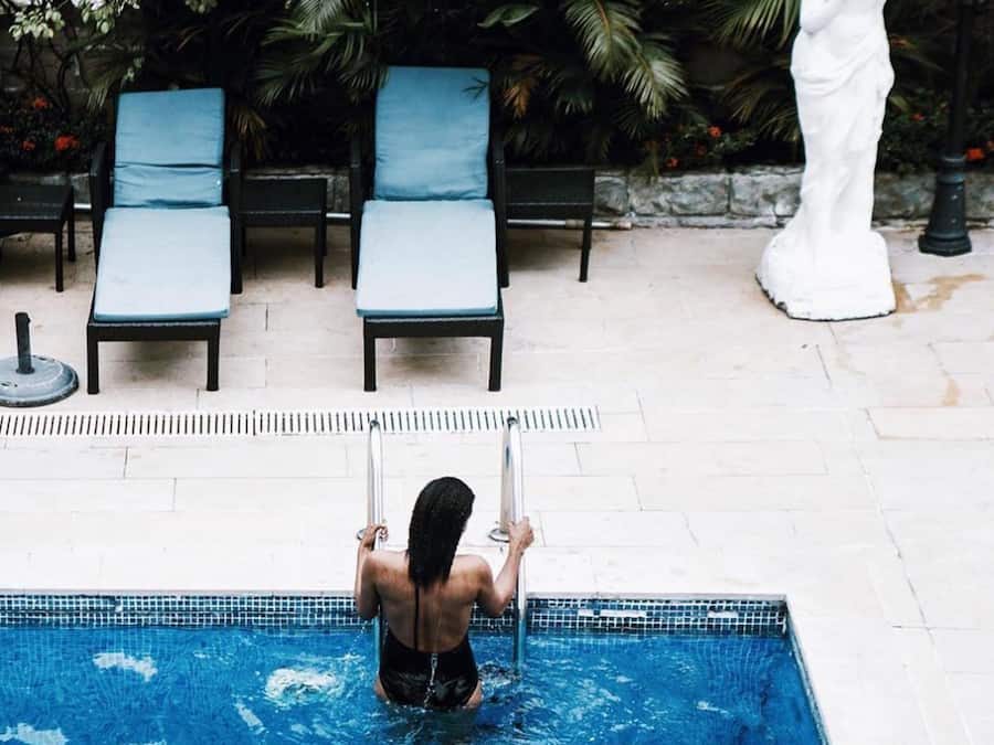 A swimming pool with lounge chairs and a statue in the background.