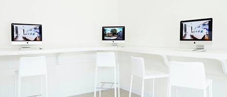 Un intérieur moderne avec trois écrans, des chaises blanches et un comptoir blanc.